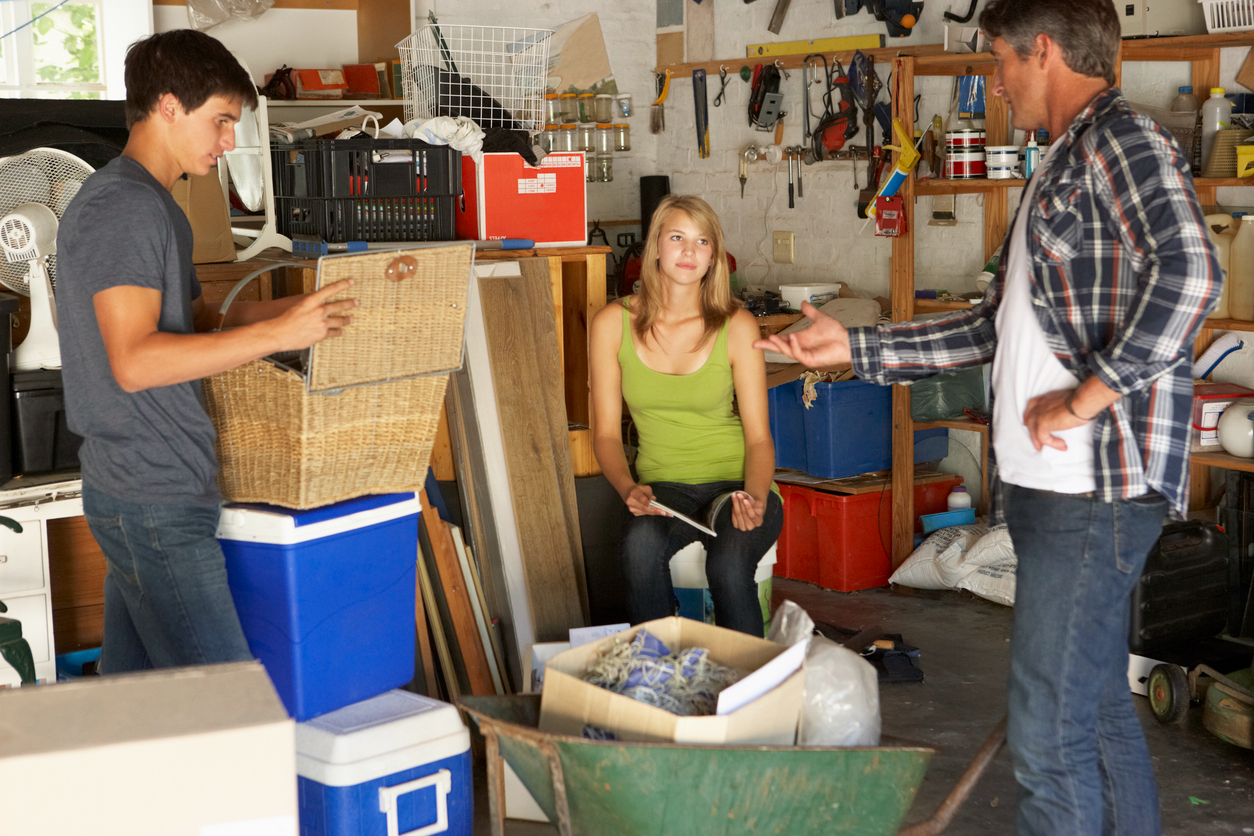 A father with his teenage daughter and son decluttering their garage. 